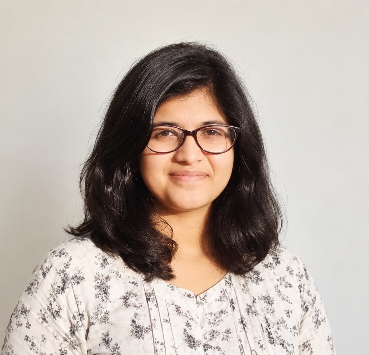Priyanka Rajeev in a floral blouse, smiling in warm natural light
